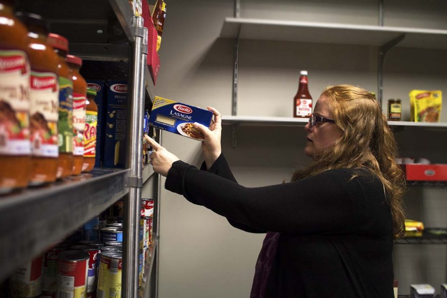 Keri Bass stocks food on the shelves in the Campus Cupboard office in Olin. Photo by Kevin Donovan