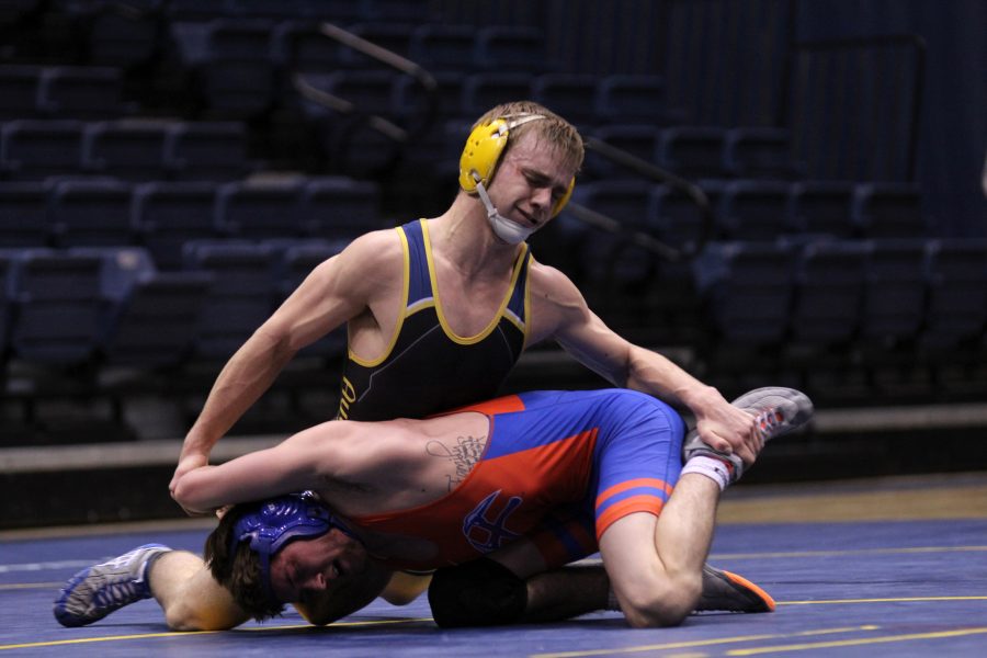 Junior Dale Charlier attempts to hold his opponent by hanging on to his leg and arm. Charlier won his individual match with a score of 4–2. Photo by Tony Dzik