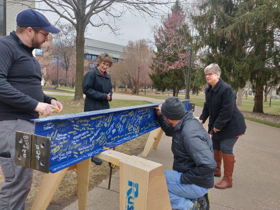 Staff members from the Chemistry Department: Greg Domski, Patrick Crawford, Pam Trotter, and Sally Burgmeier sign the support beam outside Olin on Nov. 16, 2018. Photo by Natalie McMillan. 