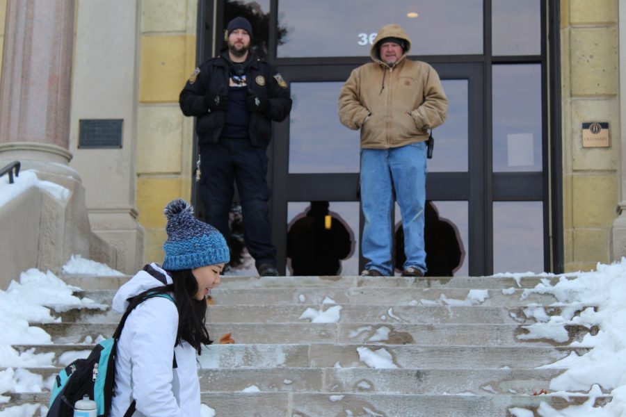 Student Rachael Heah walks past Marcus Masters, first shift Public Safety officer, and Chris Scott from the Instruction Department, who are keeping students from entering Old Main Jan. 21, 2018. 