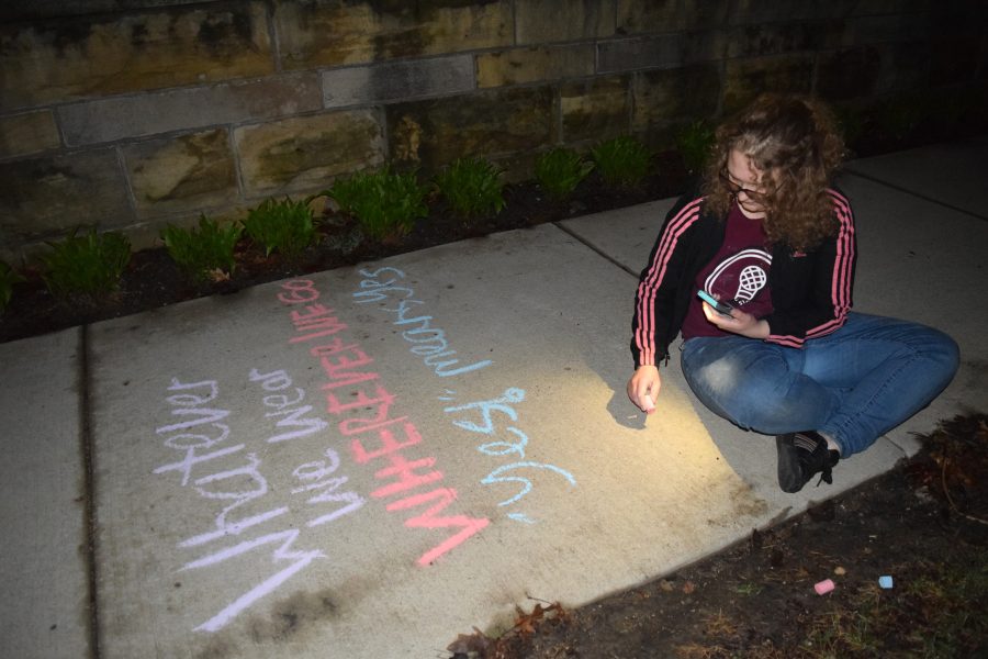 Senior Emma Nordmeyer bends down to write a message in chalk near midnight on Thursday, April 25. Members of the #MakeAChange movement chalked the lower quad, Old Main stairs and 7th avenue sidewalk. Photo by Thea Gonzales.