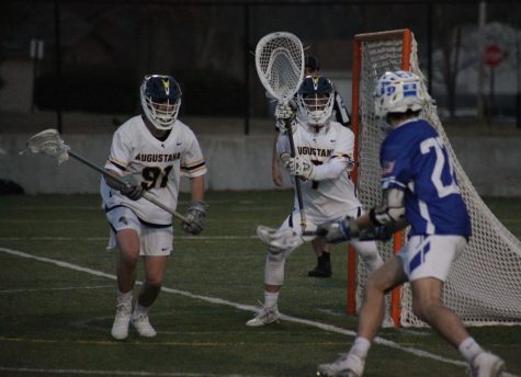 Senior and goal keeper Cameron Duffy guards the goal with junior (91) Paul Huber against Dubuque’s (22) junior Ben Farraday on March 16 at Thorson-Lucken Field. The Vikings won the game 10-6. 