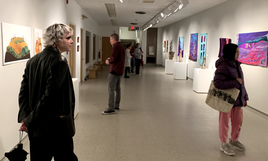 Guests and members of the Augustana community admire work at the Augustana Faculty Art Show in Centennial hall on April 8, 2022.
