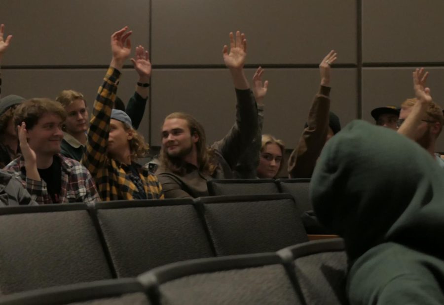 Participants raise hands to speak at town hall meeting.