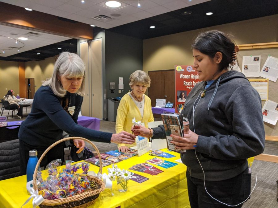 Rebecca Montgomery hands a flower to senior Lilia Rangel at the P.E.O. table on International Women’s Day on March 8, 2023. Jan Riccio is also pictured.