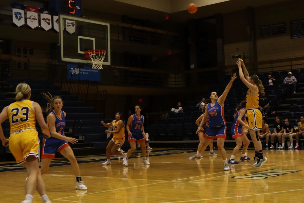 Augustana College’s Senior Corey Whitlockshoots shoots a 3-pointer while UW Platville’s Sarah Mueller blocks on Nov. 16. The Vikings were defeated, falling to the Pioneers by a score of 83-74.