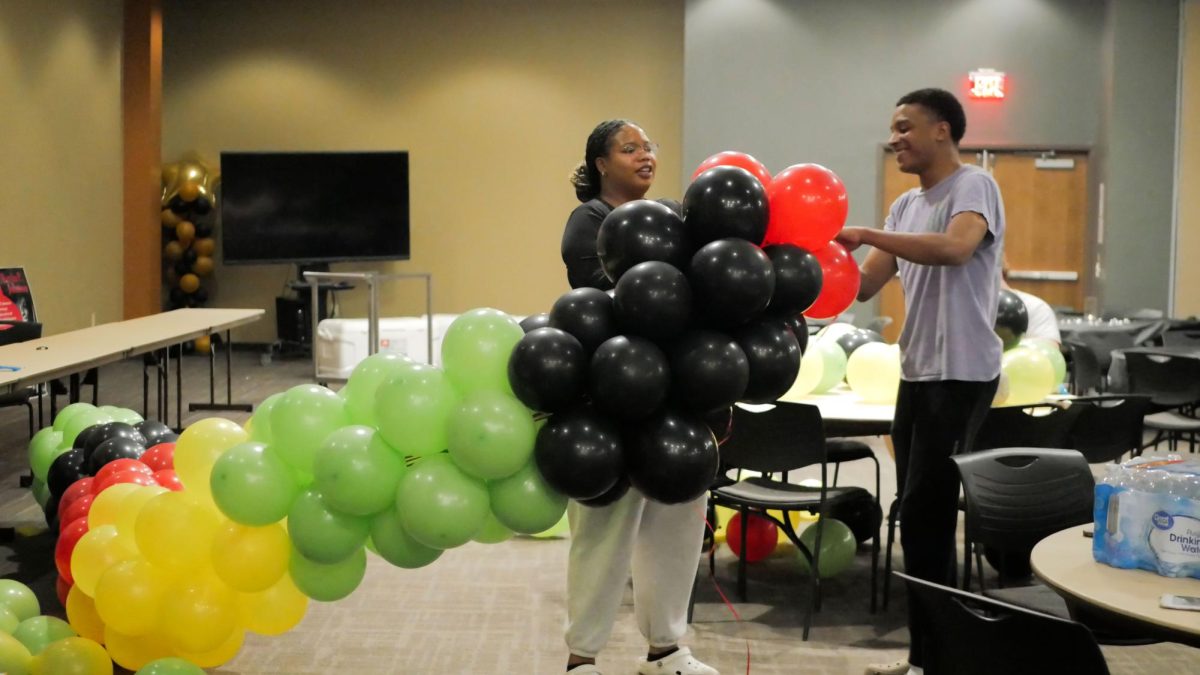 Senior Zion Thomas, president of the Black Student Union, prepares a balloon arc for the photo booth with Junior Madi Cloman, vice president of the Black Student Union, in preparation for the annual Soul Food Dinner on Feb 24, 2024. Thomas said the organization poured hours of hard work into this event.