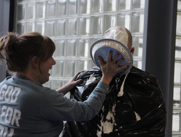 Pastor Melinda Pupillo, who had the second highest score, pies first-place Nathan Frank on Pi Day, March 14, in the Hanson Lobby. 