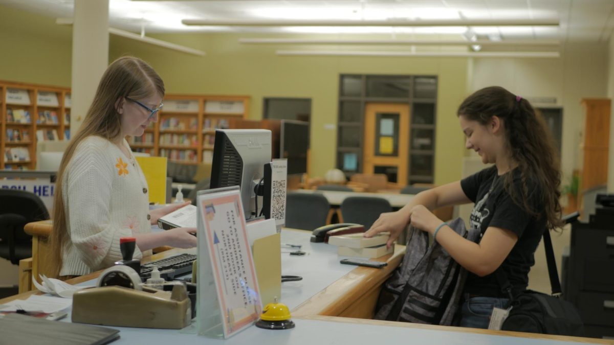 Librarian Kaitlyn Goss-Peirce helps Junior Kaitlin Troha at the library research help desk. Research librarians and student workers take on weekly shifts to be present at the desk to help students navigate the library and their research.