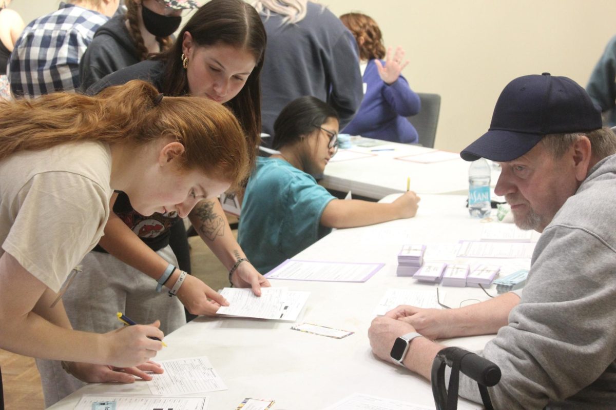 Augie students fill out the Benefits Application at the Social Service Station at the Experiential Reentry Simulation on Oct. 9 in Wallenberg Hall under the guidance of the APEP volunteer Tim Downey.